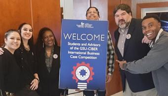 CCD students posing with professors in front of a Welcome sign.
