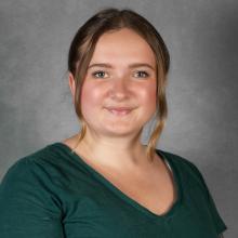 Woman with pulled-back blond hair wearing dark green top