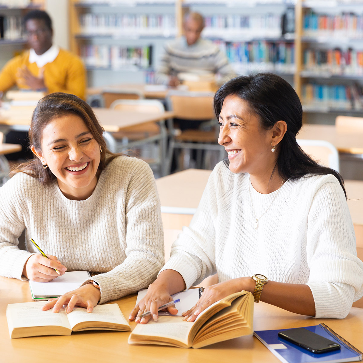 two women at a table reading books