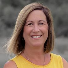 Woman with mid length light brown hair wearing a yellow top