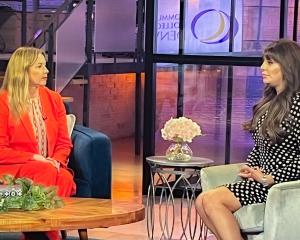Dr. DeSanctis in red business attire sitting down talking to a woman with long, brown hair. 