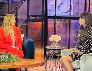 Dr. DeSanctis in red business attire sitting down talking to a woman with long, brown hair. 