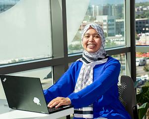 Students sitting at a tables on their laptops and iPads