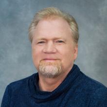 Person with a goatee wearing a dark blue shirt