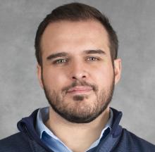 Albert Teixeira is a white male with short dark hair and wearing a blue collared sweater over a light blue button down