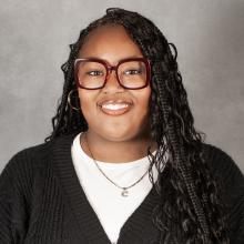 woman with long Brunette braids wearing red glasses and black sweater